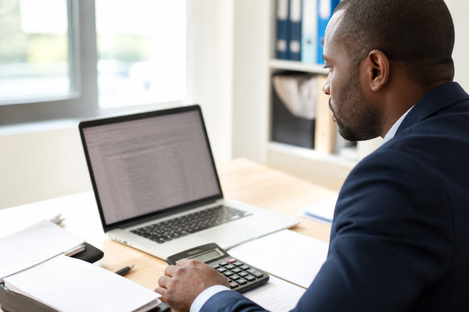 Chauffeur VTC calculant sa TVA sur un ordinateur portable avec une calculatrice